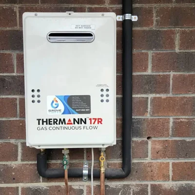 Installed hot-water unit with Grove Plumbing and Gas service sticker